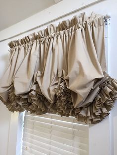 the curtains are hanging on the window sill in front of the window with white shutters