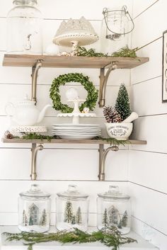 the shelves in this kitchen are filled with dishes and christmas wreaths on top of them