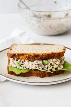 a sandwich on a plate with lettuce and chicken salad in the middle next to a bowl