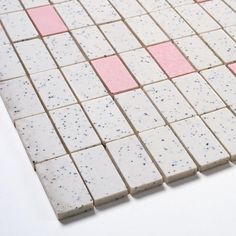 pink and white tiles are arranged on the floor with one red dot in the middle