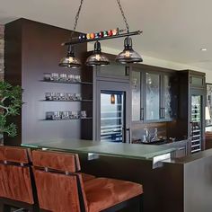 a kitchen with two bar stools next to an island and wine glasses on the shelves