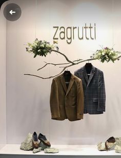 two suits and shoes are on display in front of a sign that says zagrutu