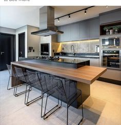 a modern kitchen with stainless steel appliances and wooden counter tops, along with bar stools