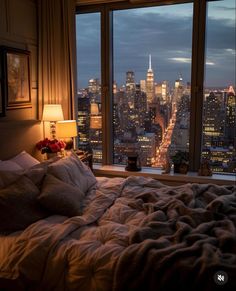 a bedroom with a view of the city lights and skyscrapers from it's windows