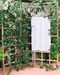 a wooden trellis with plants growing on it and a white sign in the middle