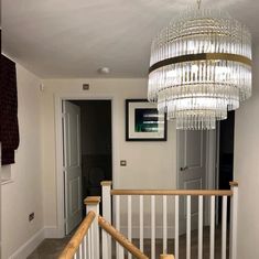 a chandelier hanging from the top of a wooden banister in a hallway