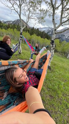 two women sitting in hammocks with their feet on the ground and one woman holding her leg up