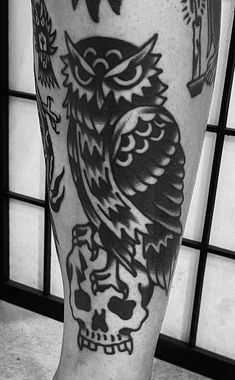 an owl tattoo on the leg of a person with a skull and crossbones