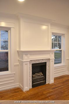 an empty living room with wood floors and white walls, including a fire place in the center