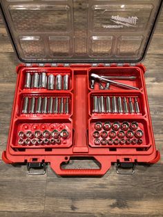 an open tool box filled with tools on top of a wooden floor next to a pair of wrenches