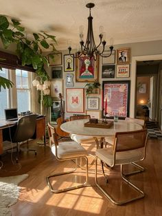 a dining room table with chairs and pictures on the wall above it, in front of a window