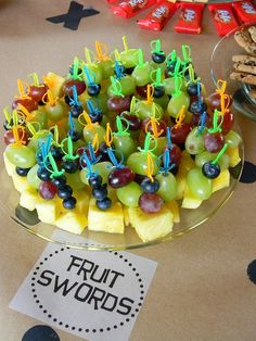 a platter filled with grapes, pineapples and blueberries next to cookies