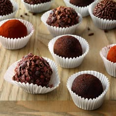 chocolate truffles are lined up on a wooden table with red powder in them