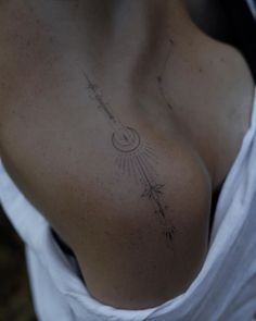 a woman's chest with an arrow tattoo on her left side, and stars in the sky