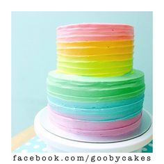 a multi colored cake sitting on top of a white plate next to a polka dot table cloth