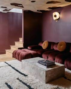 a living room with purple walls and red couches in the center, white rugs on the floor