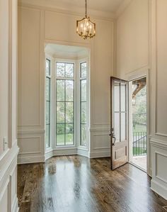 an empty room with wood floors and white walls, two doors leading to the outside