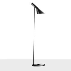 a black floor lamp sitting on top of a white table next to a light bulb