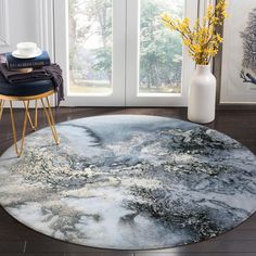 a round rug in the middle of a room next to a vase with yellow flowers