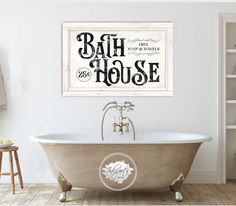 an old fashioned bathtub in a white bathroom with wood flooring and wall decor