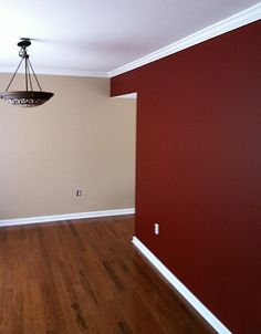 empty room with hard wood flooring and red painted walls, chandelier hanging from the ceiling