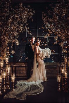 a bride and groom standing in front of candles