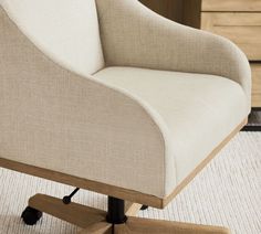 an office chair sitting on top of a white rug next to a wooden desk with drawers