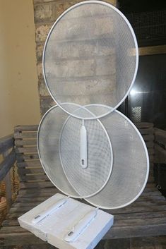 three white round baskets sitting on top of a wooden table next to a brick fireplace