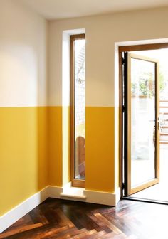 an empty room with wooden floors and yellow walls