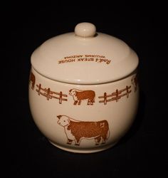 a brown and white cow covered dish on a black surface with words written in red