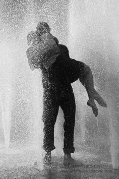 a man and woman are hugging in the water fountain while they both have their arms around each other