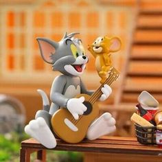 a figurine of a cat playing the guitar with a mouse on top of it