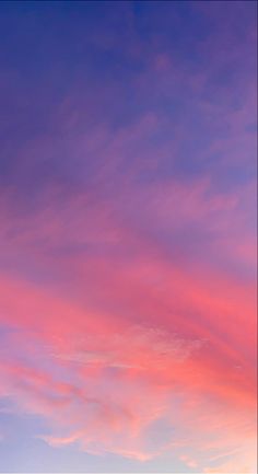 an airplane is flying in the sky with pink and blue clouds behind it at sunset