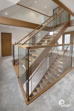 a glass and wood staircase in an empty room with carpeted flooring on both sides