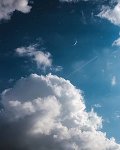 an airplane flying in the sky with some clouds below it and a half moon at the top