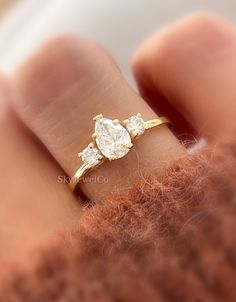 a woman's hand with a yellow gold ring and two pear shaped diamonds on it