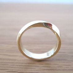 a close up of a wedding ring on a wooden table with wood grained surface