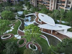 an aerial view of a building surrounded by trees and grass in the middle of a park