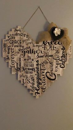 a wooden heart hanging on the wall with words written all over it in black and white