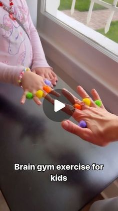 two children are playing with their hands on the table and one child is holding something in her hand