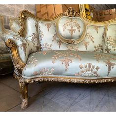 an ornate couch with gold trim and blue upholstered fabric, in front of a mirror