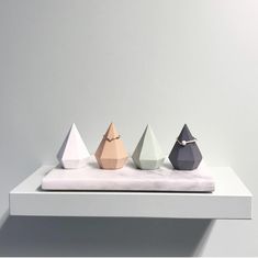 three different colored vases sitting on top of a white shelf