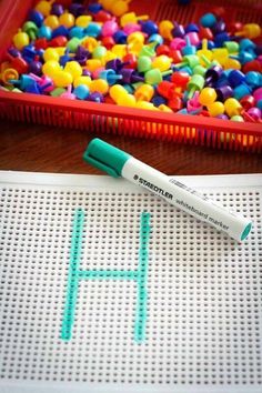 a marker sitting on top of a piece of paper next to a plastic container filled with beads