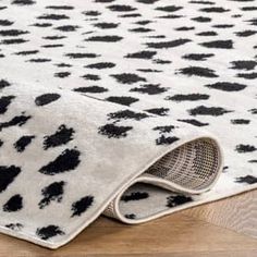 a rug with black and white spots is on the floor in front of a wooden floor