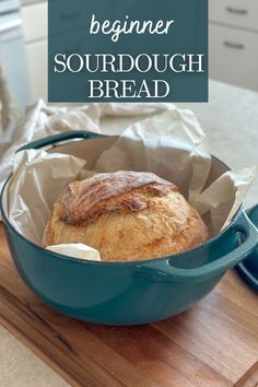 a loaf of bread sitting in a blue pan on top of a wooden cutting board