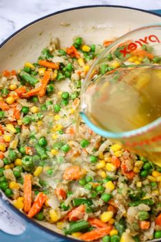 a pot filled with rice and vegetables being poured into it