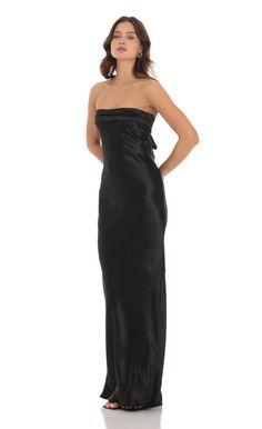 a woman in a black strapless dress standing with her hands on her hips and looking off to the side