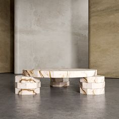 a white marble table sitting on top of a cement floor next to a gray wall