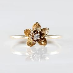 a yellow gold flower ring with two white diamonds on the middle and one brown diamond in the middle