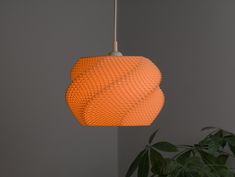 an orange lamp hanging from a ceiling next to a potted plant